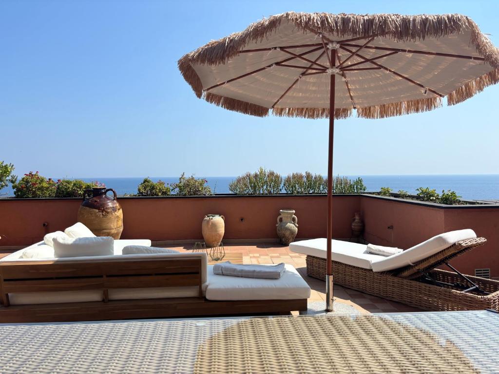 a patio with two beds and an umbrella at Casa Della Baia With a beautiful view in Varazze