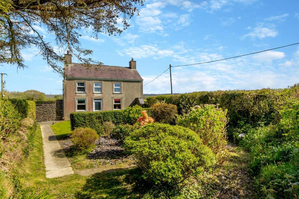 una casa vieja en medio de un jardín en Maenllwyd, en Llanrhystyd