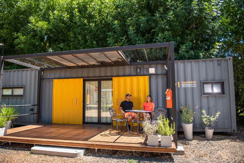 deux personnes assises à une table dans une petite maison dans l'établissement EcoMódulos Termas Villa Elisa, à Villa Elisa