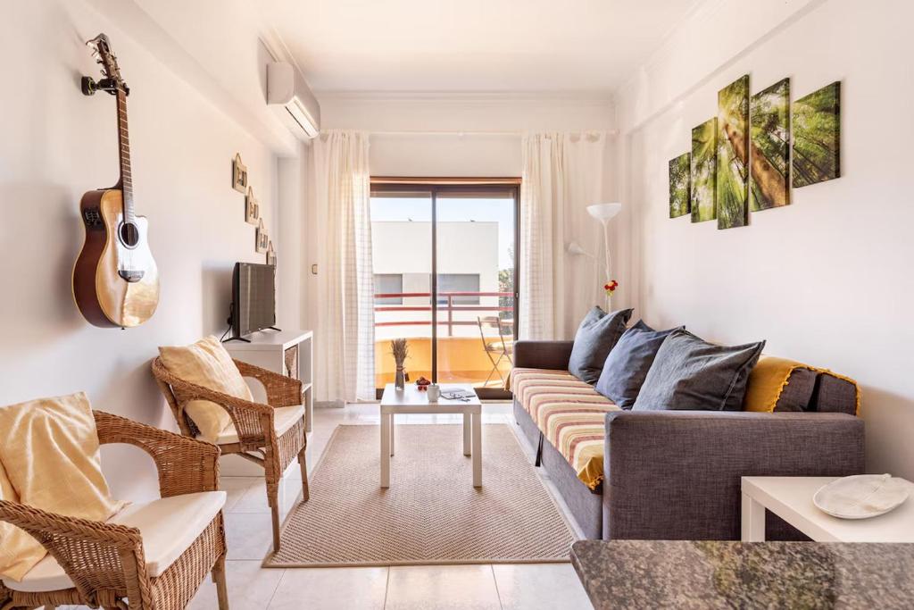 ein Wohnzimmer mit einem Sofa und einer Gitarre in der Unterkunft GuestReady - Deluxe home with terrace in Caparica in Costa da Caparica