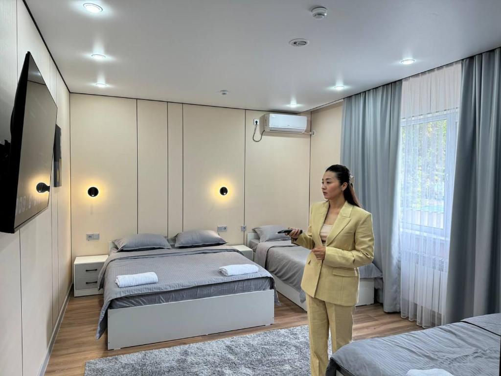 a woman standing in a room with two beds at Damir HOTEL ГОСТИНИЦА in Aktobe