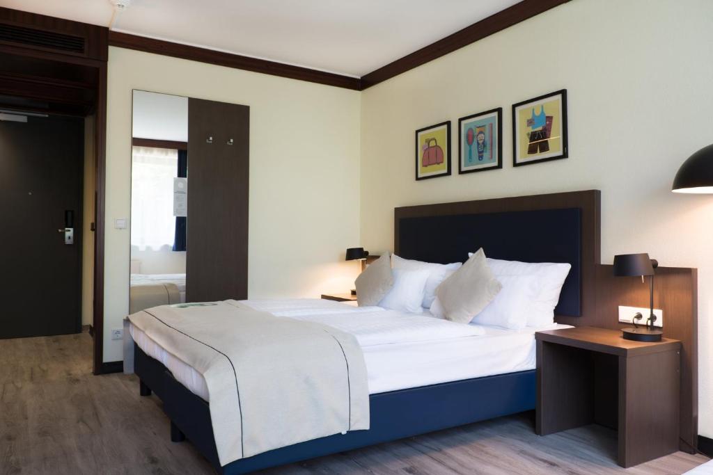 a bedroom with a large white bed and a table at Garner Hotel Frankfurt - Palmengarten by IHG in Frankfurt/Main