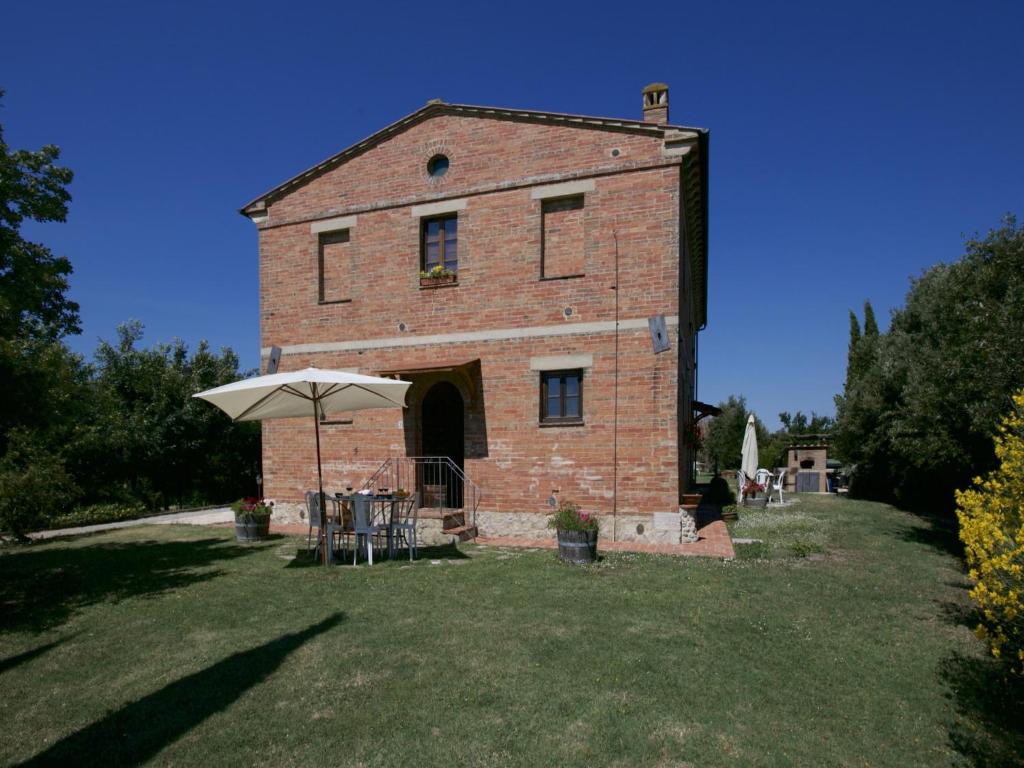 a large brick building with an umbrella in the yard at Farmhouse in Tuscany near Siena & Hot Springs in Castelnuovo Berardenga