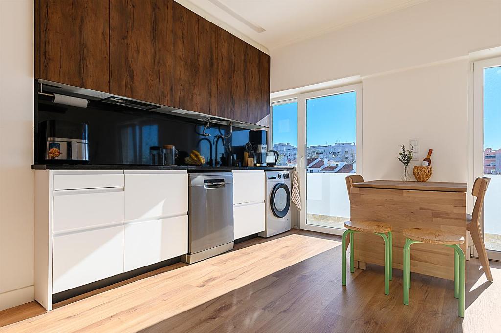 a kitchen with white cabinets and a table with a wooden tableablish at Almada Comfort in Almada