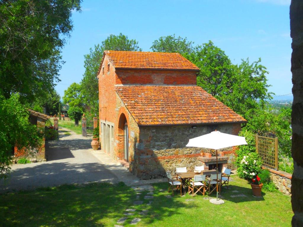 a small brick building with a table and an umbrella at Cottage in Val di Chiana in Castiglion Fiorentino