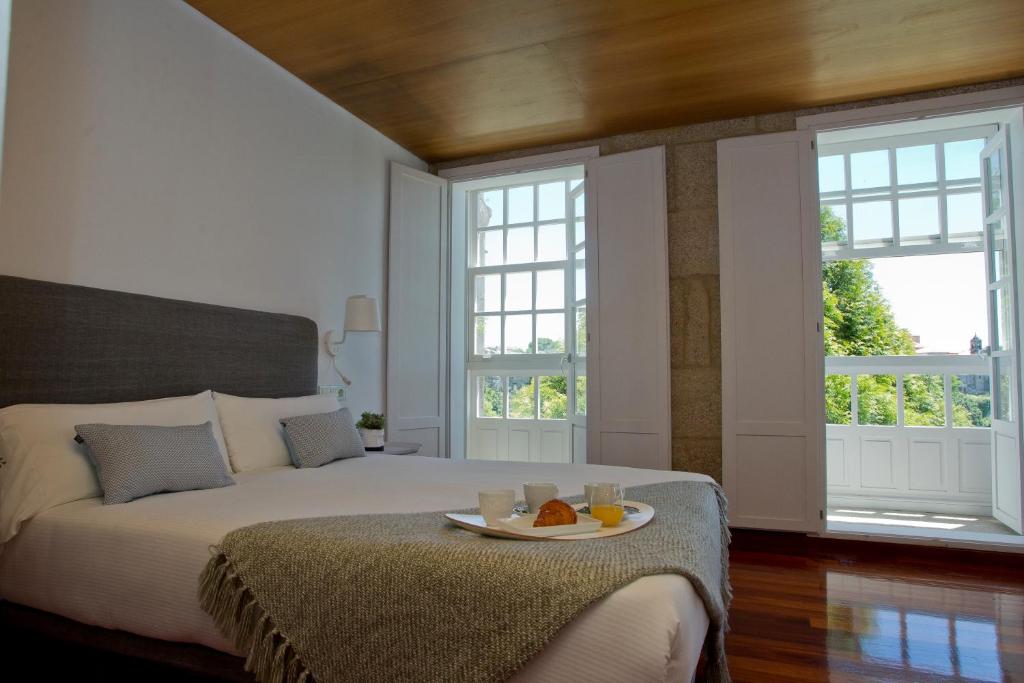 Un dormitorio con una cama con una bandeja de comida. en Pensión O Xardin de Julia, en Santiago de Compostela