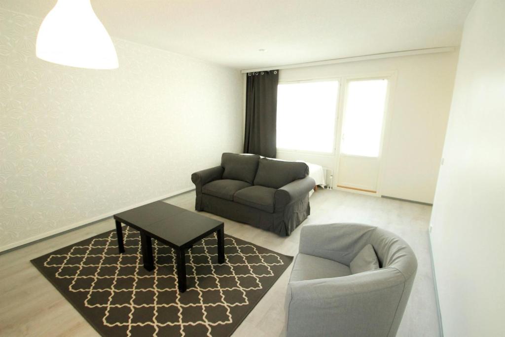 Una sala de estar con un sofá, una silla y una mesa. en Central and Spacious Apartment for 4 with Sauna, en Äänekoski
