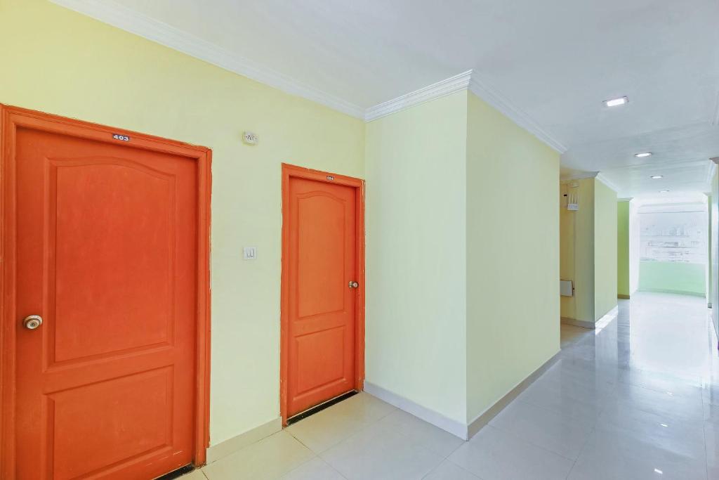 a hallway with two red doors and a white wall at Super Hotel O Golden Hive Madhapur Near Shilparamam in Hyderabad