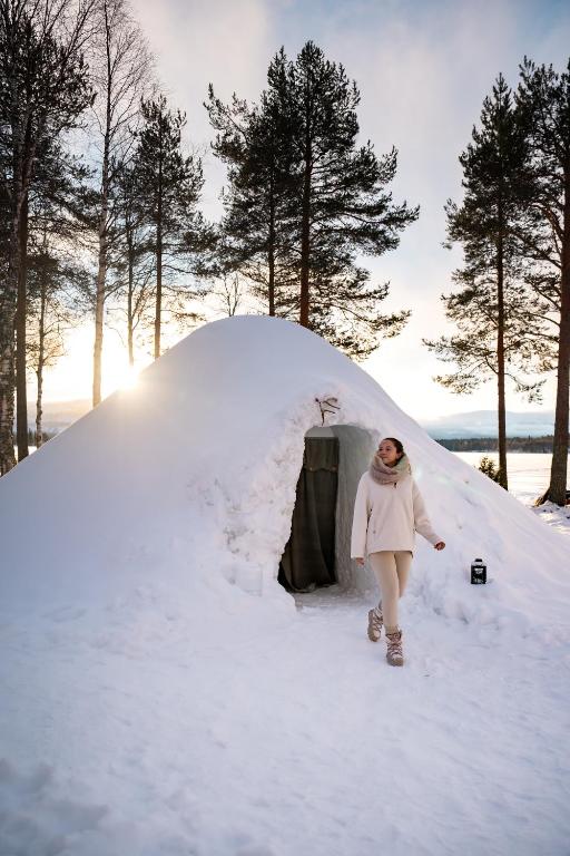 a woman walking past a igloo in the snow at Lucky Ranch Snow Igloos in Pyhätunturi