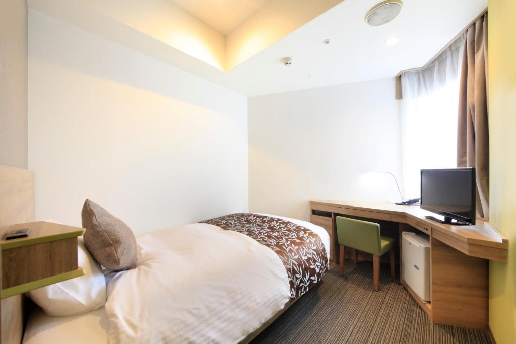 a hotel room with a bed and a desk with a computer at Hotel Sunshine Utsunomiya in Utsunomiya