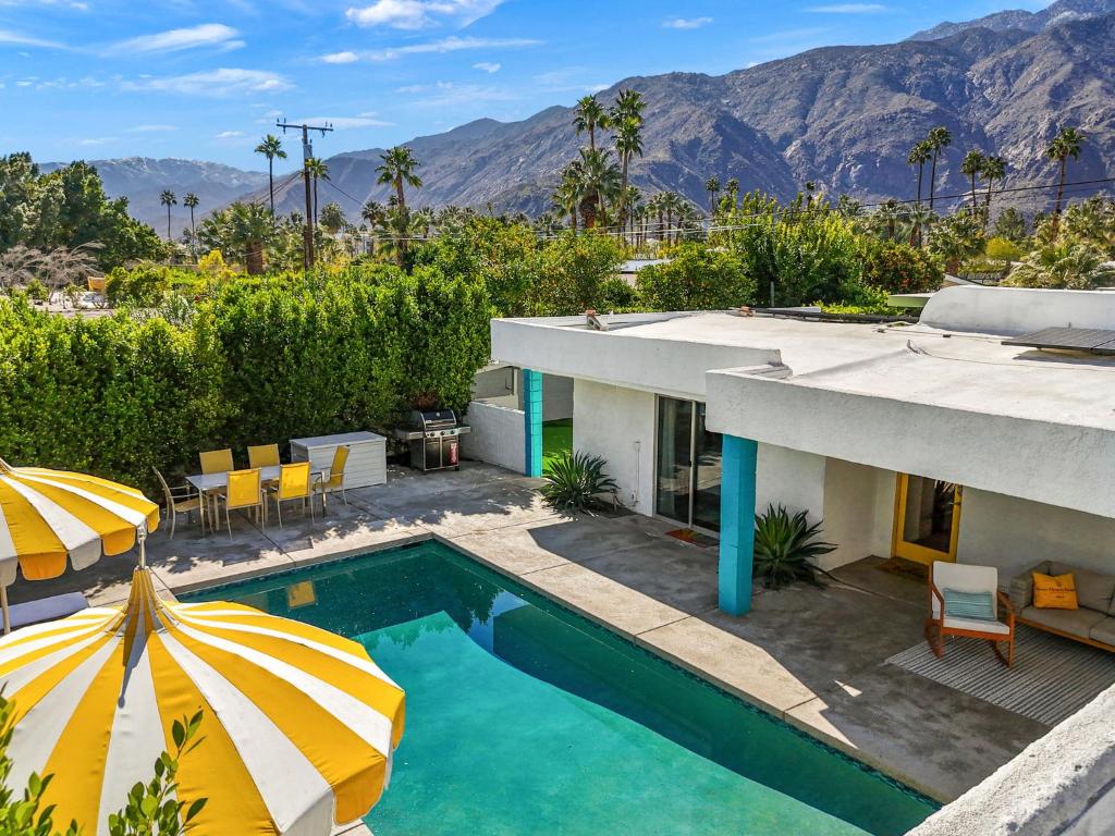 a house with a swimming pool and two umbrellas at The Ricardo! Mid-Century Villa with Saltwater Pool in Palm Springs