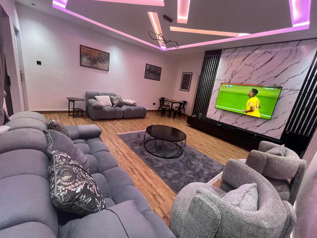 a living room with couches and a large screen tv at MedeHeights Apartments in Abuja