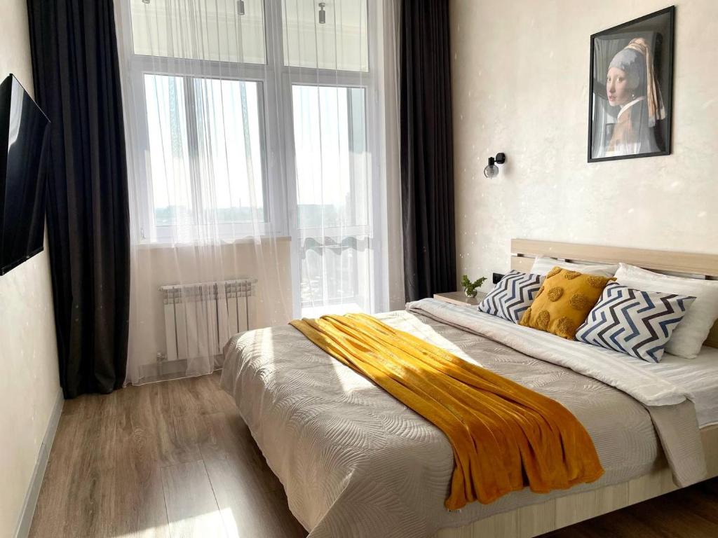 a bedroom with a large bed with a large window at Уютные Апартаменты 1 Минута от Станции Метро in Almaty