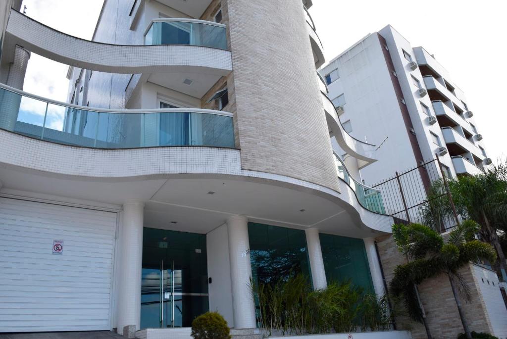 a large white building with a white garage at Suítes Trindade in Florianópolis