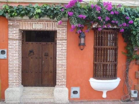an orange building with a door with flowers on it at Colonial Luxury Oasis In Cartagena's Old City in Cartagena de Indias