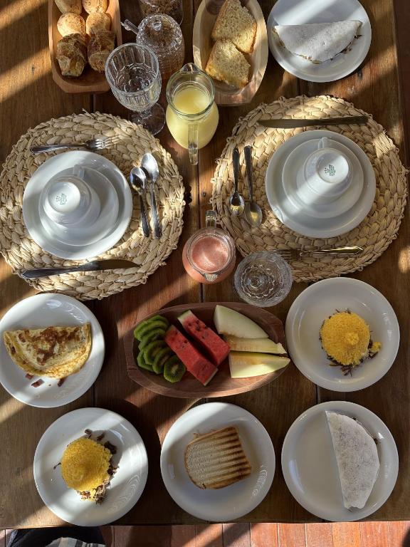 a wooden table with plates of food on it at Pousada Suyhê in Caraíva