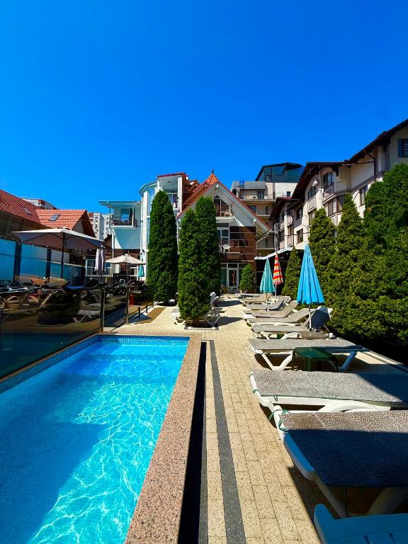 a swimming pool with lounge chairs and umbrellas at Hotel Kalyan & Spa in Chişinău