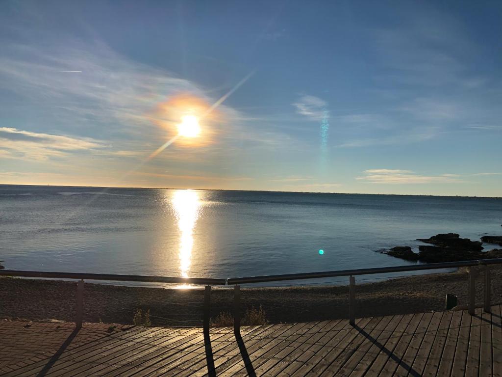 a view of the ocean with the sun reflecting on the water at Apartament L'Ampolla BLAU a 50 m del MAR, WIFI, parking in L'Ampolla