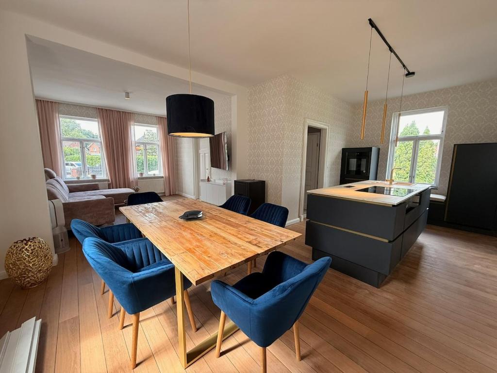a kitchen and dining room with a wooden table and blue chairs at Renoviertes Haus am Sommerdeich in Freiburg - Elbe
