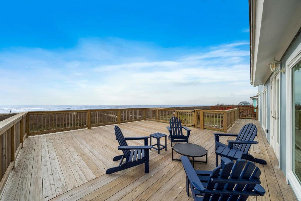 a deck with chairs and a table with a view of the ocean at Our Infinity Pool in Galveston