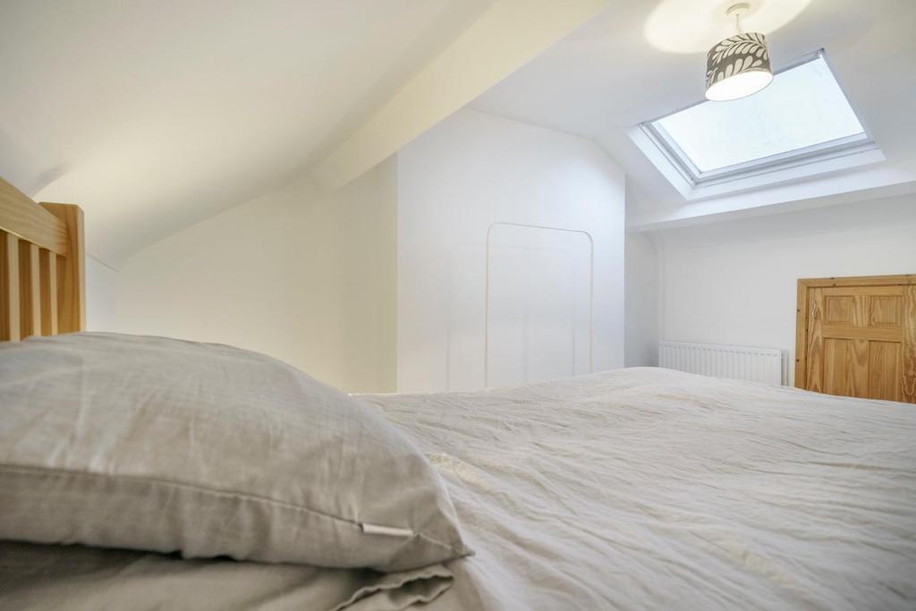 a white bedroom with a bed and a skylight at Close to Belfast City Centre Townhouse in Belfast
