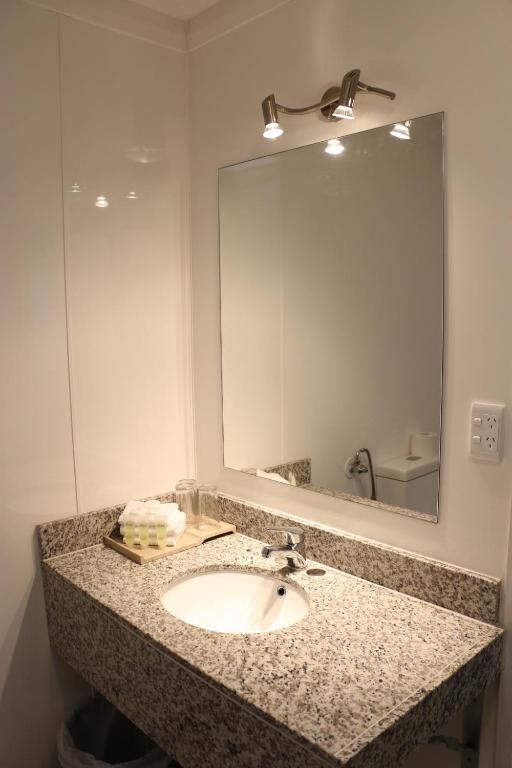 a bathroom with a sink and a large mirror at Airport Gateway Hotel in Auckland