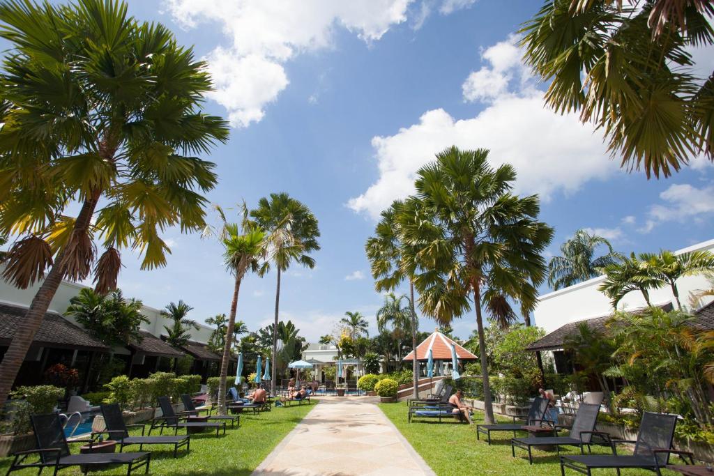 un parque con palmeras y sillas y una acera en Access Resort & Villas - SHA Plus, en Karon Beach