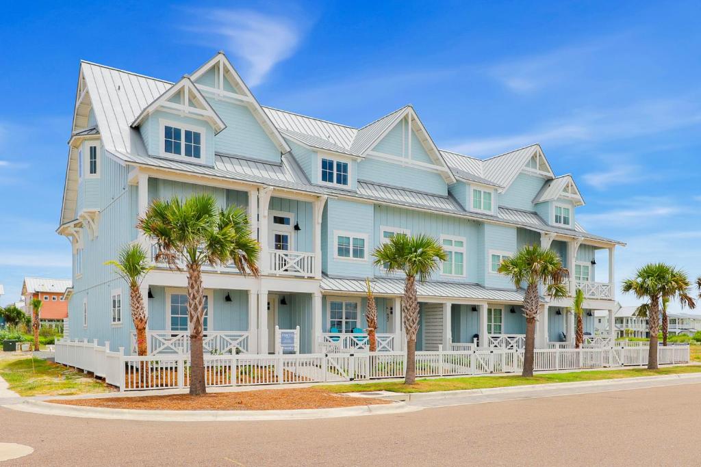 a large blue house with palm trees in front of it at Sunset Shores Escape in Port Aransas