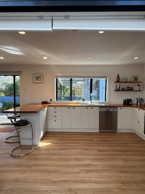 a kitchen with white cabinets and a wooden floor at Clive Cottage in Clive