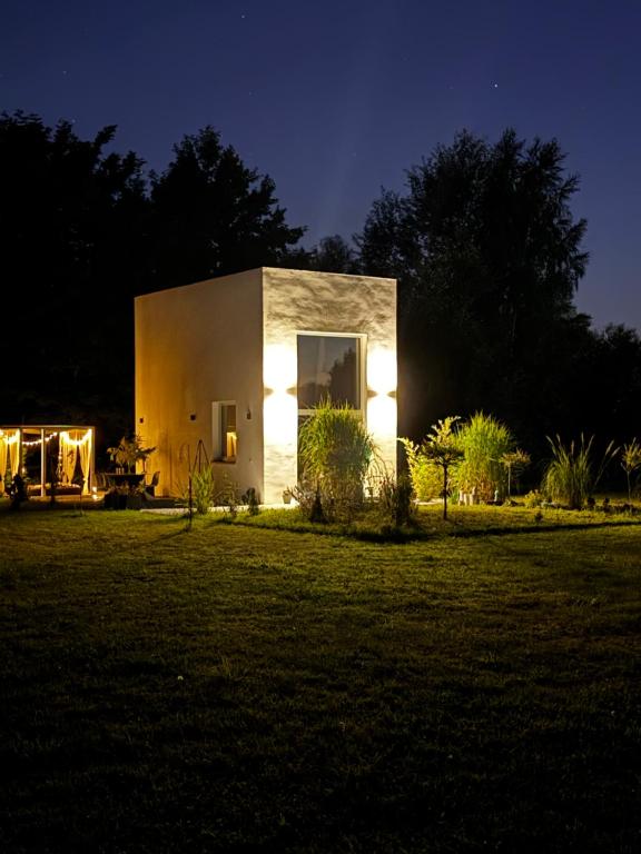 a small house with lights in a yard at night at Awangarda in Trzciel