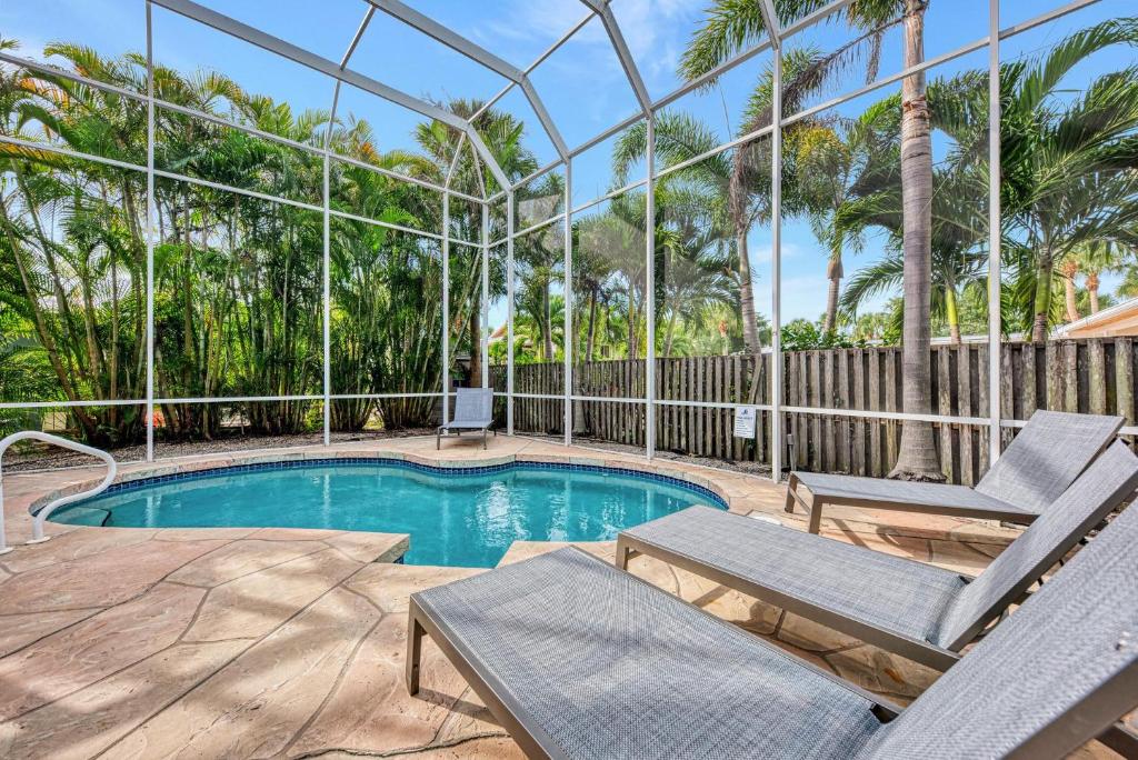 une piscine avec deux chaises longues à côté d'une clôture dans l'établissement Surf's Up, à Siesta Key