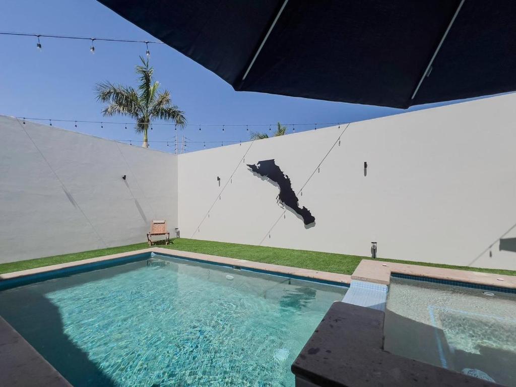 a large swimming pool in a building with an umbrella at Casa Delfines, 2Br home in quiet neighborhood 10 min from downtown in La Paz