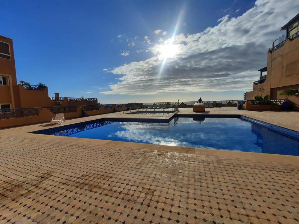 ein Schwimmbad mit der Sonne am Himmel in der Unterkunft Tamraght apartment with Pool access in Tamraght Ouzdar