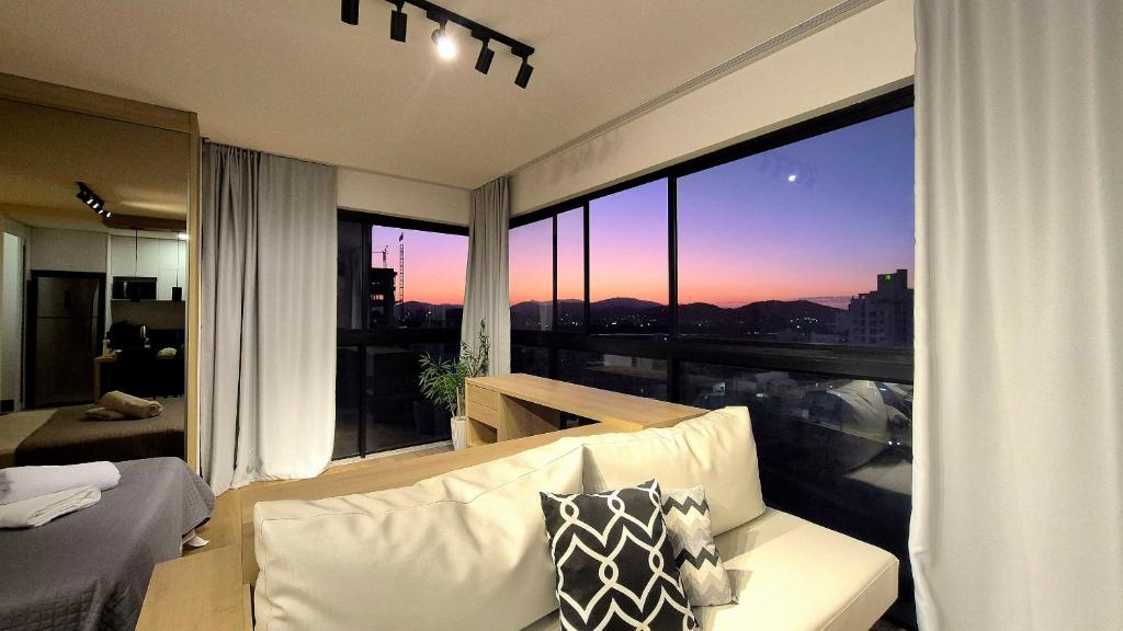 a living room with a couch and a large window at CURTA! |165| Lindo Studio | Próx Centro de Eventos in Camboriú