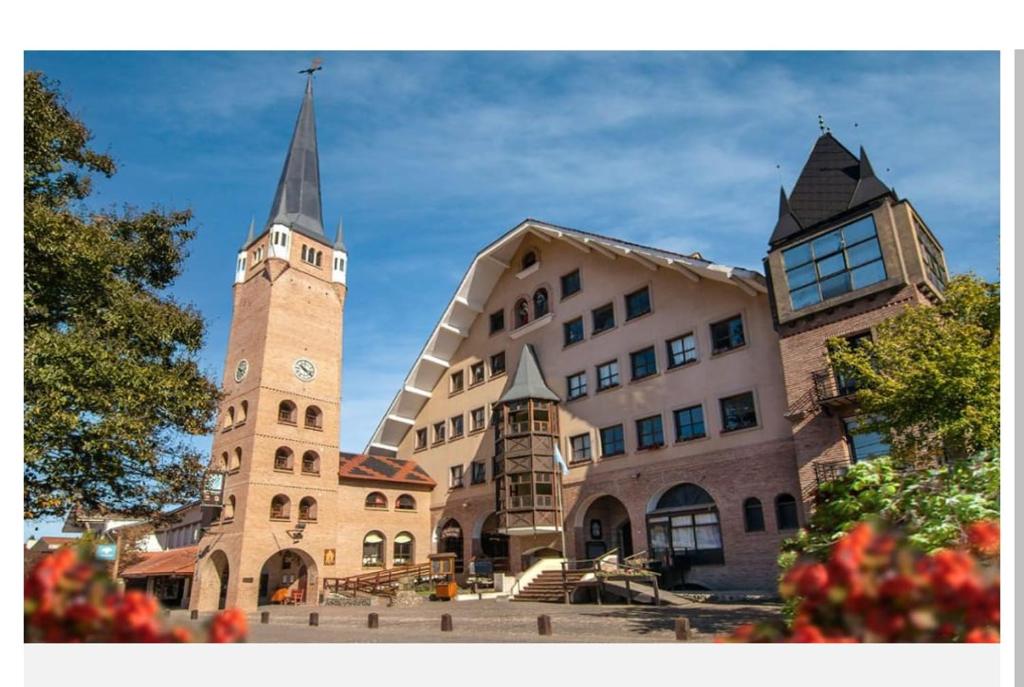 un edificio con una torre de reloj al lado de una iglesia en HolaViajerosVGB, en Villa General Belgrano