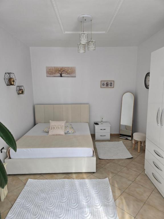 Un dormitorio blanco con una cama y un espejo. en Cozzy Studio Tirana, en Tirana