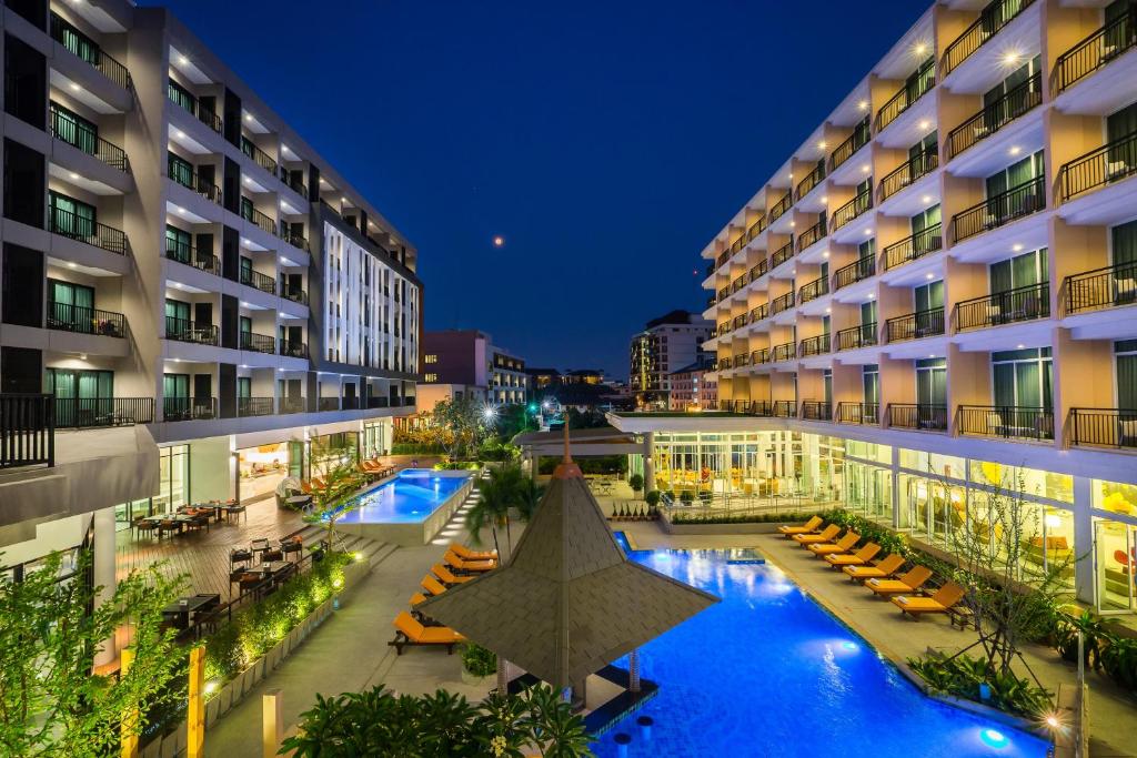 een binnenplaats van het hotel met een zwembad in de nacht bij Hotel J Pattaya - SHA Extra Plus in Pattaya