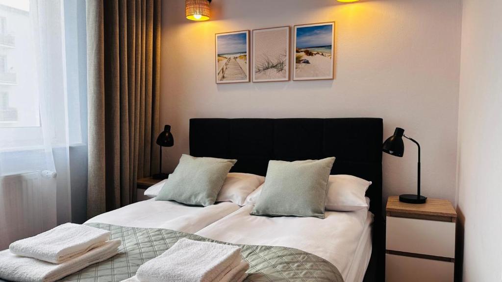 un dormitorio con una cama con dos almohadas en Apartament Dworcowa z widokiem na park, en Kołobrzeg