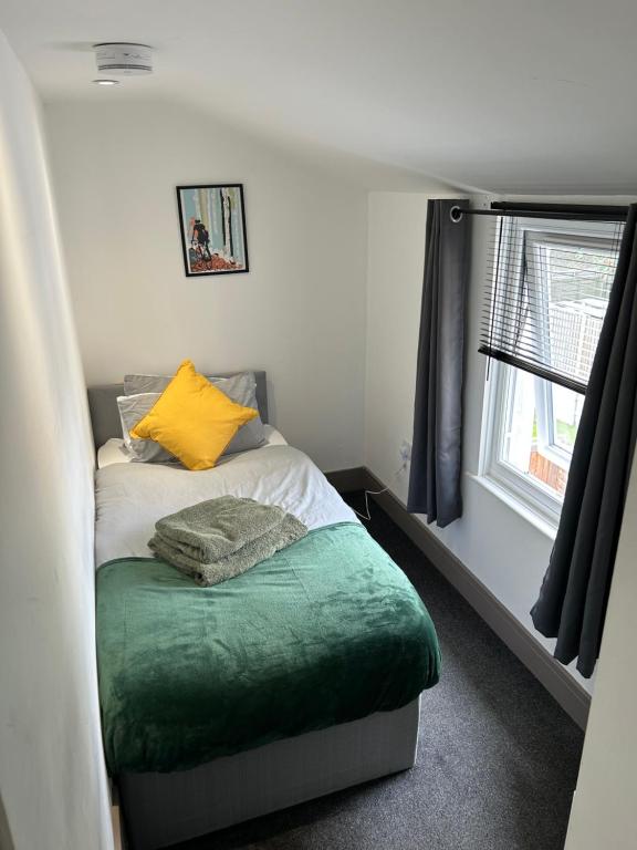 a small bedroom with a bed with a yellow pillow at Saunders Lodge 4bedroom house sleeps up to 6 in Gillingham