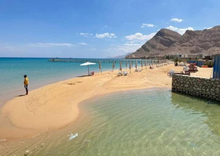 a man standing on a beach next to the water at Ground peaceful chalet 3 bedroom with 6 king bed & 2 bathrooms &private garden marvelous land escape Murano resort Ain sokhna in Ain Sokhna