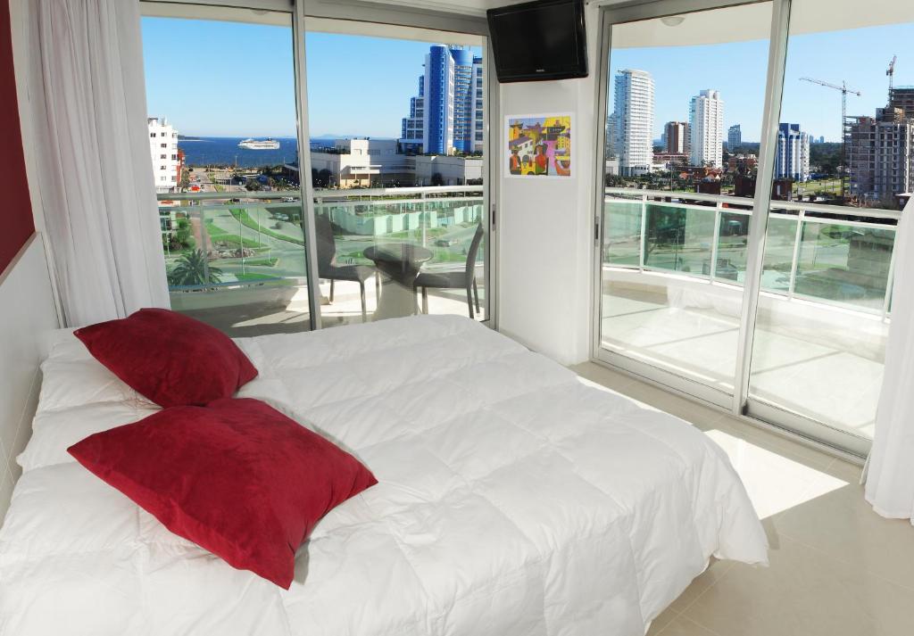 a bedroom with a white bed with red pillows at Sol y Luna 2 Punta del Este - Apartamentos Full Amenities in Punta del Este
