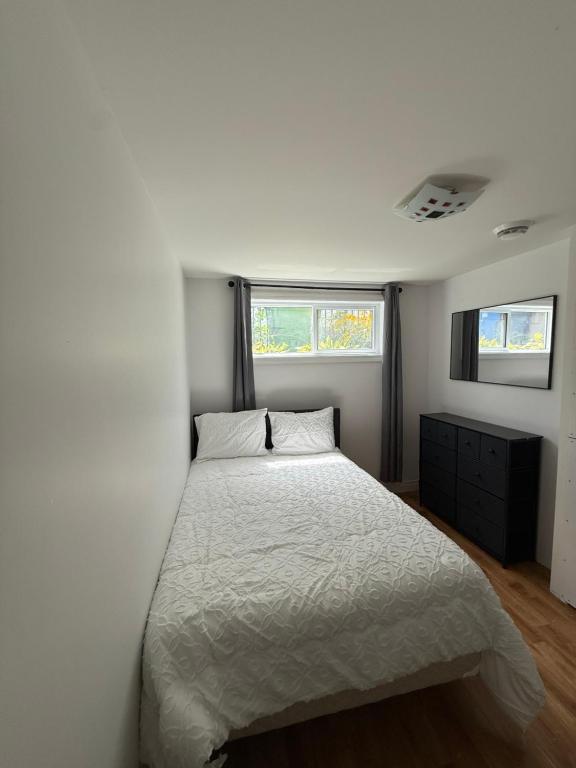 a bedroom with a white bed and two windows at Naomie in Sainte-Catherine