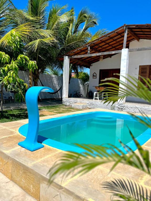 a pool with a blue dolphin statue next to a house at Casa Naurú in Fortim
