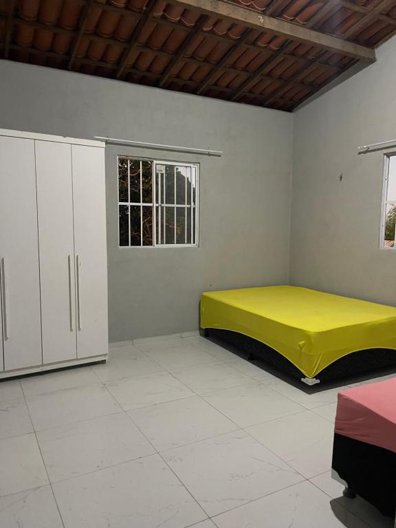 1 dormitorio con cama amarilla y armarios blancos en Chácara recanto do girassol, en Aquiraz