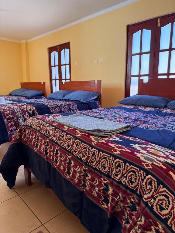two beds in a room with windows at Hostal La Alborada in Cajamarca