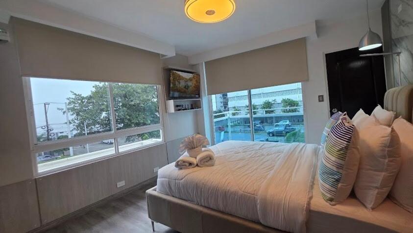 a bedroom with a large bed with large windows at Excepcional Apartamento en Ave Balboa N#4 in Panama City