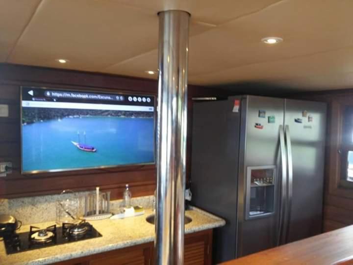a kitchen with a refrigerator and a tv with a boat on it at IBIZA Escuna in Paraty