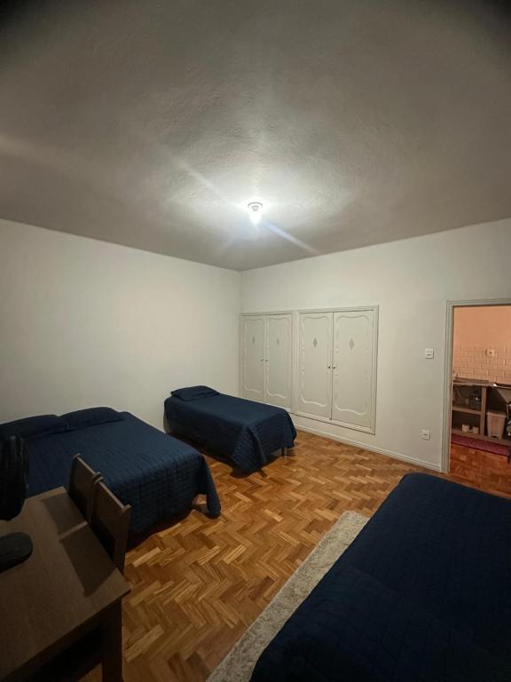 a bedroom with two beds and a table in it at Quarto Aconchegante in Belo Horizonte