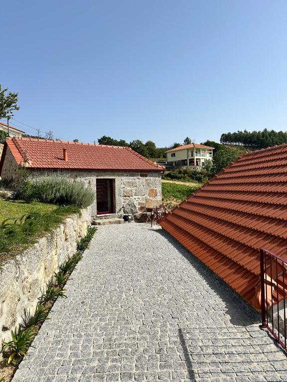 a stone pathway leading to a building with a red roof at Quinta de Águas Mortas in Gestaco