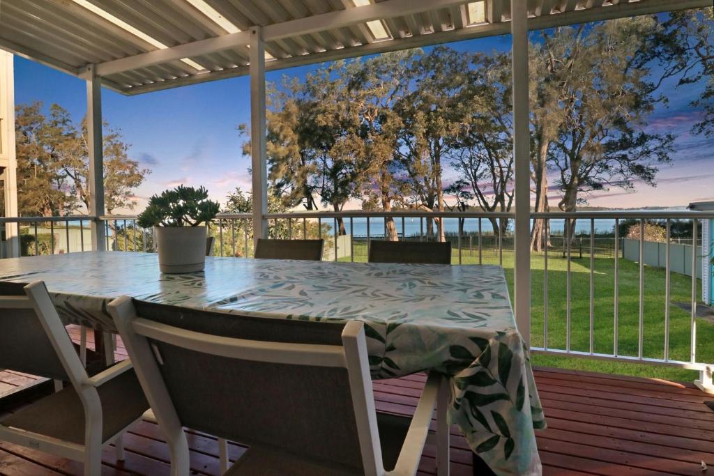 a table and chairs on a porch with a view of the ocean at Lake Front Home Relax Unwind in Budgewoi